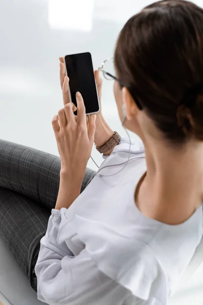 Businesswoman in earphones using smartphone — Stock Photo