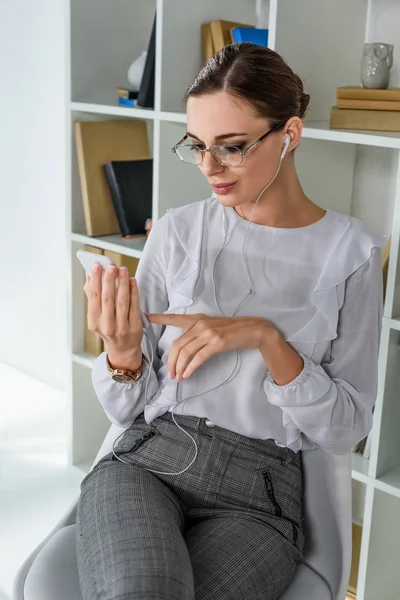 Geschäftsfrau mit Kopfhörer per Smartphone — Stockfoto