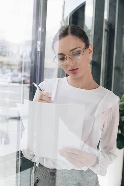 Empresária escrevendo sobre papelada — Fotografia de Stock