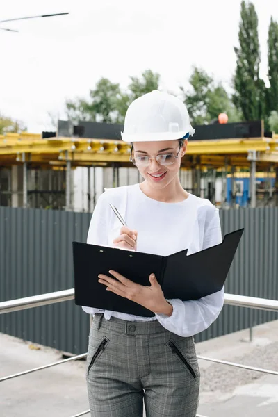 Femme d'affaires au chantier de construction tenant dossier — Photo de stock