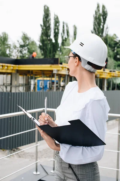 Businesswoman in hardhat watching construction — Stock Photo