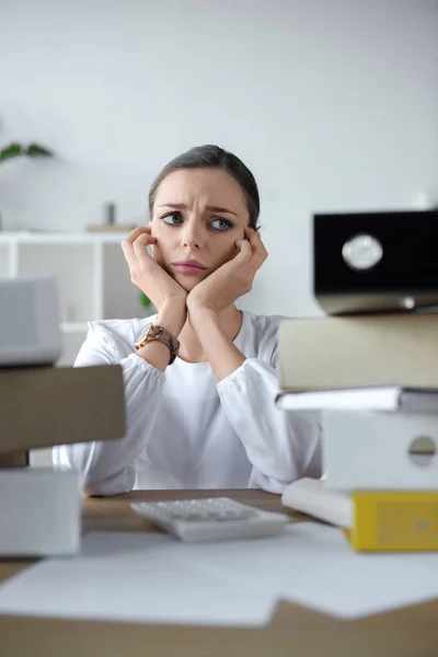 Traurige Geschäftsfrau blickt auf Aktenstapel — Stockfoto