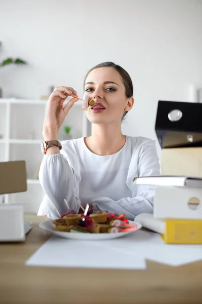 Businesswoman eating tea sandwich — Stock Photo