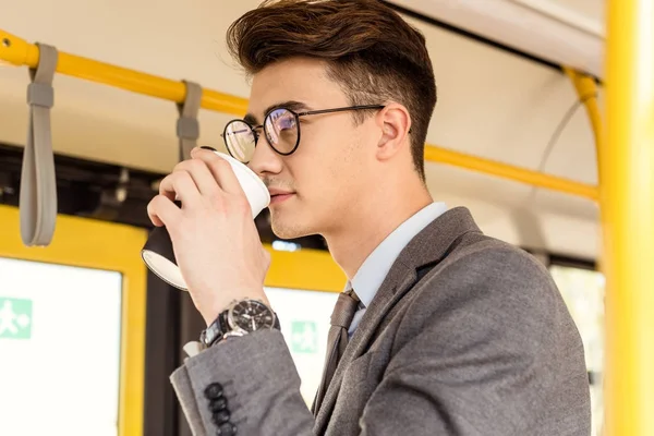 Hombre con café para ir en transporte público - foto de stock
