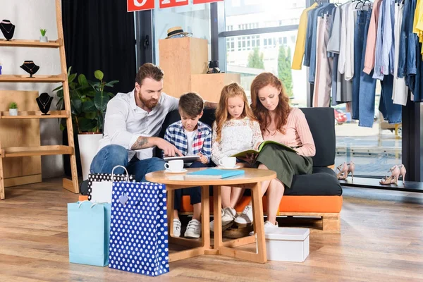 Family reading magazines in boutique — Stock Photo