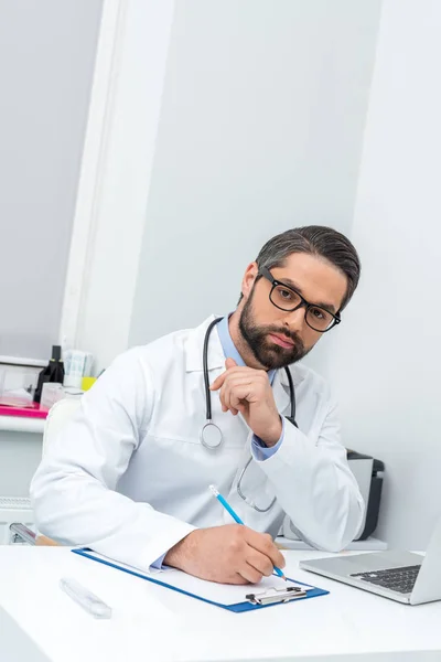 Doctor escribiendo en portapapeles - foto de stock