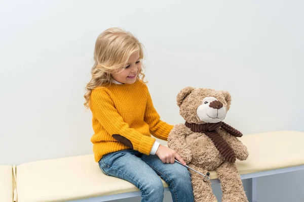 Girl doing neurology examination of teddy bear — Stock Photo