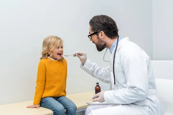 Pediatra dando mezcla a chica - foto de stock