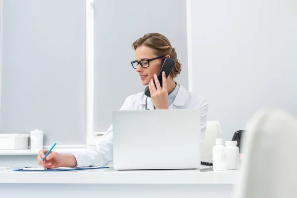 Female doctor talking by phone — Stock Photo