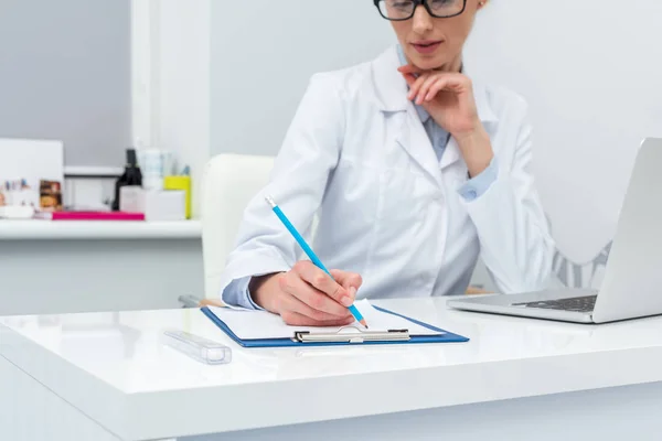 Женщина-врач пишет в блокноте — стоковое фото