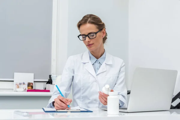 Femme médecin écriture dans le presse-papiers — Photo de stock