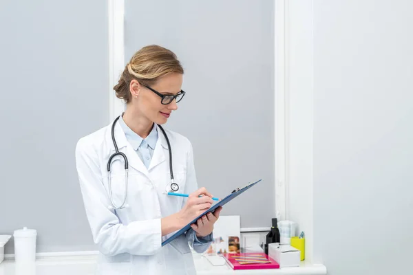 Doctora escribiendo en portapapeles - foto de stock