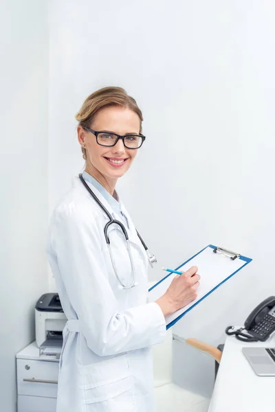 Doctora escribiendo en portapapeles - foto de stock