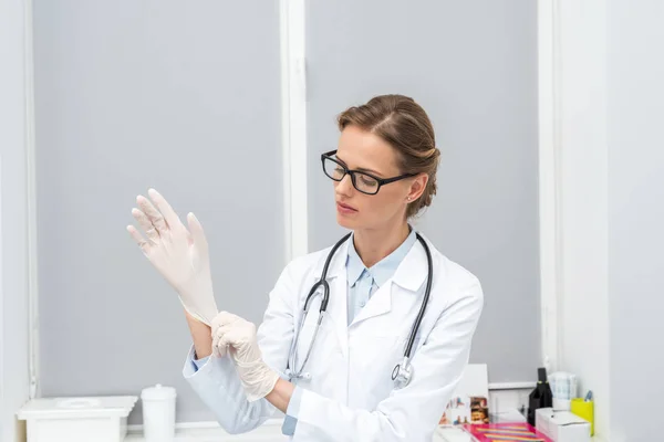 Жінка-лікар надягає рукавички — стокове фото