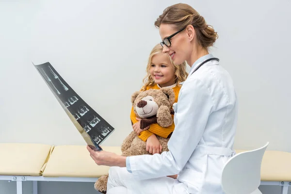 Doctor mostrando rayos X a un pequeño paciente - foto de stock