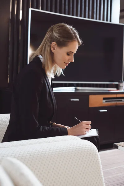 Geschäftsfrau macht sich Notizen im Hotelzimmer — Stockfoto