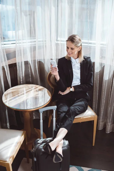 Mujer de negocios usando teléfono inteligente en la habitación de hotel - foto de stock