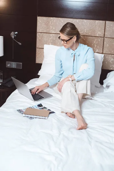 Femme d'affaires utilisant un ordinateur portable dans la chambre d'hôtel — Photo de stock