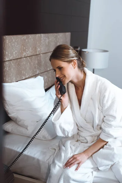 Woman in bathrobe talking by phone — Stock Photo