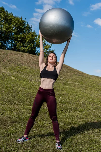 Woman holding fitball over head — Stock Photo