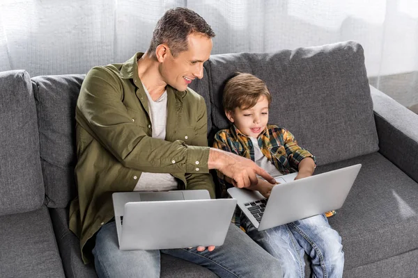 Padre e hijo usando computadoras portátiles - foto de stock