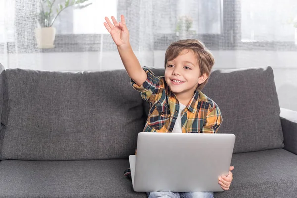 Niño con portátil sentado en el sofá - foto de stock