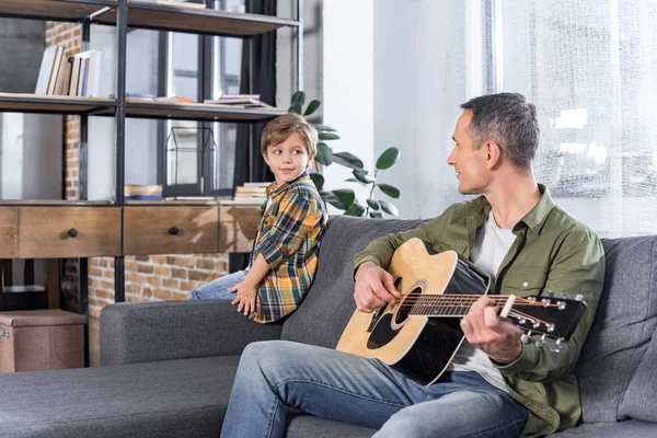 Отец играет на гитаре для сына — стоковое фото