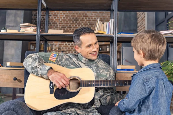 Military man playing guitar for son — Stock Photo