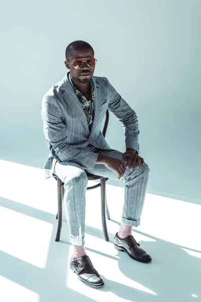 Young man in sunglasses posing on chair — Stock Photo