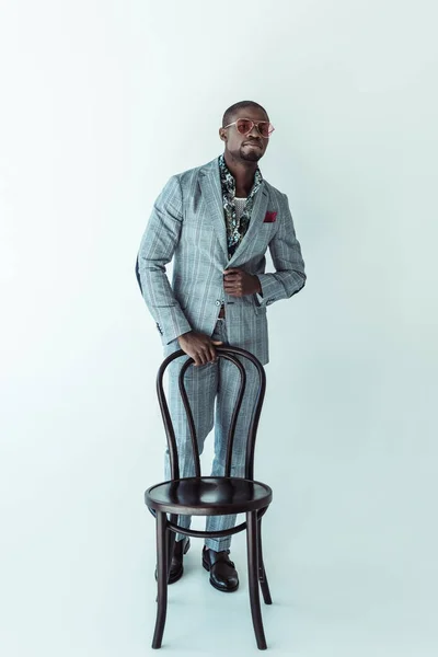 Чоловік в модному костюмі позує зі стільцем — стокове фото