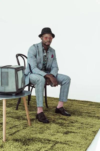 Uomo elegante in occhiali da sole e vestito sulla sedia — Foto stock