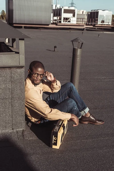 Hombre afroamericano sentado en la azotea con boombox - foto de stock