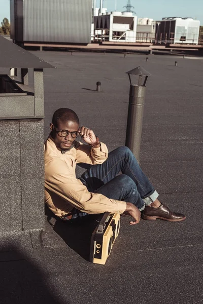 African american man sitting on rooftop with boombox — Stock Photo