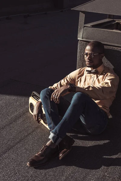 Élégant homme afro-américain assis sur le toit — Photo de stock