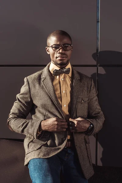 Elegante hombre afroamericano ajustando chaqueta - foto de stock