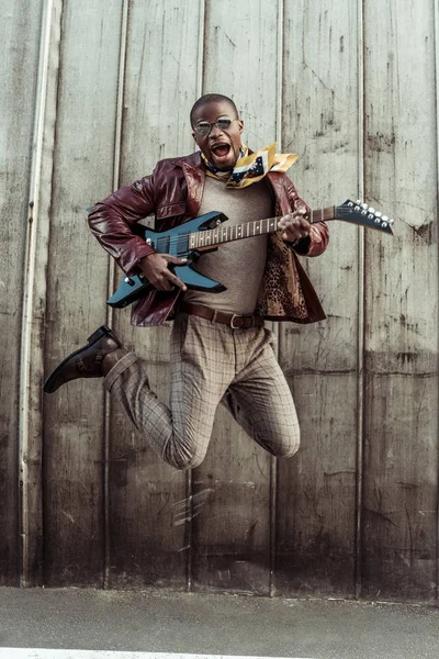 Homme élégant sautant avec guitare — Photo de stock