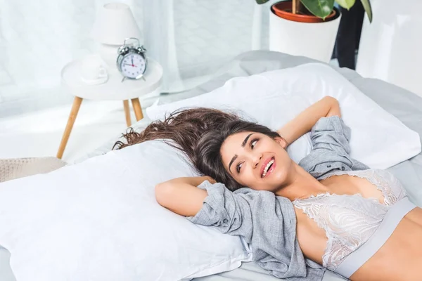 Jeune femme en lingerie sur le lit — Photo de stock