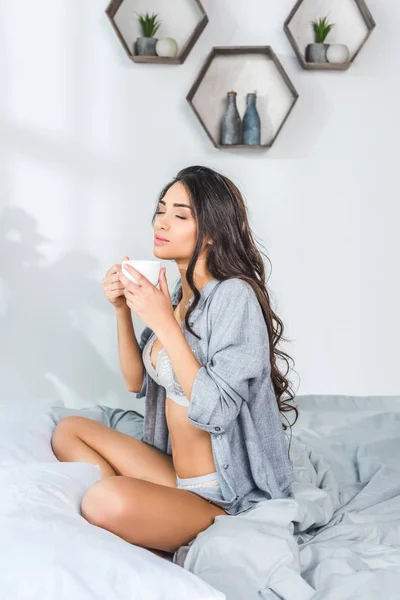 Девушка в нижнем белье пьет кофе — стоковое фото