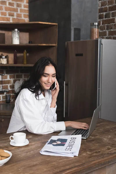 Femme parlant par téléphone et utilisant un ordinateur portable — Photo de stock