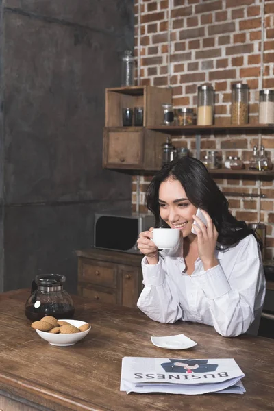 Женщина разговаривает по телефону и пьет кофе — стоковое фото