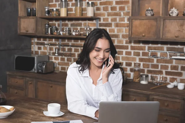 Woman talking by phone and using laptop — Stock Photo