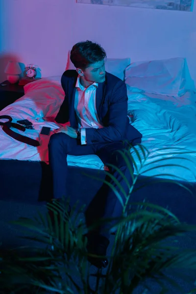 Empresário sentado na cama no quarto escuro — Fotografia de Stock