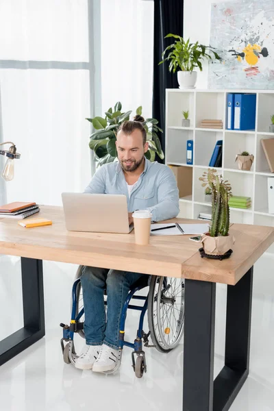 Homme d'affaires en fauteuil roulant travaillant avec un ordinateur portable — Photo de stock