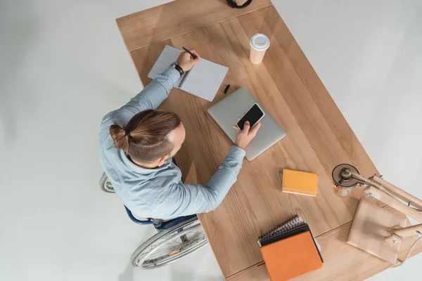 Hombre en silla de ruedas usando smartphone - foto de stock