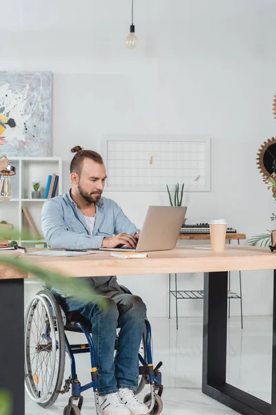 Man on wheelchair working with laptop — Stock Photo