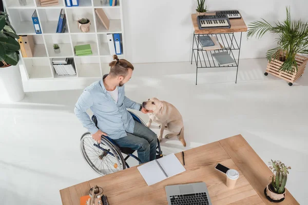 Man on wheelchair petting his dog — Stock Photo