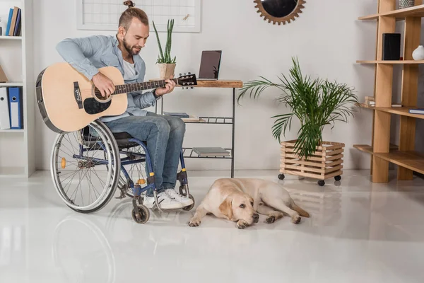 Uomo sulla sedia a rotelle suonare la chitarra — Foto stock