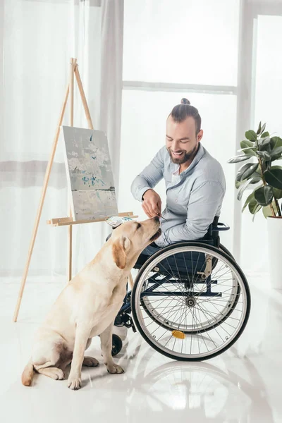 Hombre discapacitado pintar y acariciar perro - foto de stock