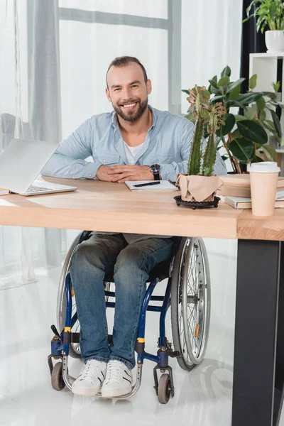 Hombre en silla de ruedas sentado en la oficina - foto de stock
