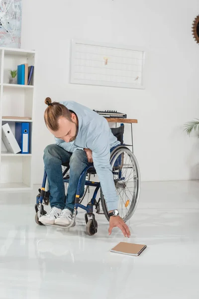 Homme en fauteuil roulant essayant d'atteindre pour le livre — Photo de stock